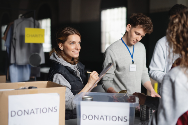 A group of volunteers working in community charity donation center, sorting out clothes and canned food.