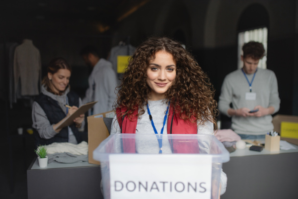 A woman volunteer working in community charity donation center, looking at camera.