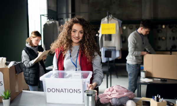 A woman volunteer working in community charity donation center, looking at camera.