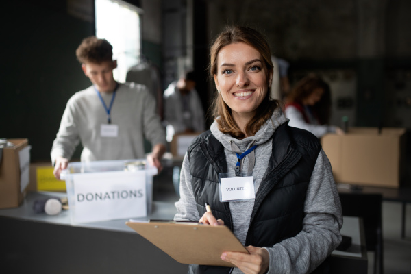 A woman volunteer working in community charity donation center, looking at camera.