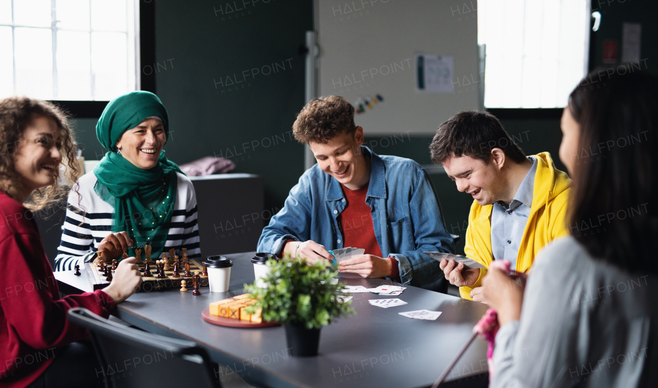 Group of happy people playing cards and board games in community center, inclusivity of disabled person.