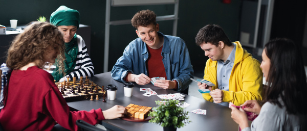 Group of happy people playing cards and board games in community center, inclusivity of disabled person.