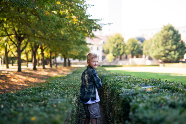 A happy little boy turning round and looking at camera when walking outoodrs in park