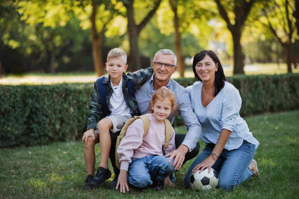 Happy little children with grandparents looking at camera outdoors in a park