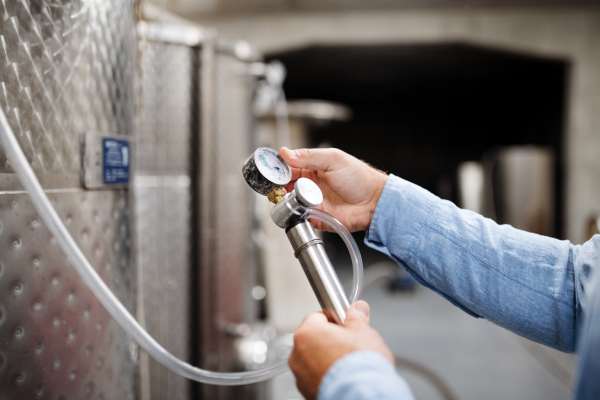 Midsection of unrecognizable man worker indoors, wine making concept.