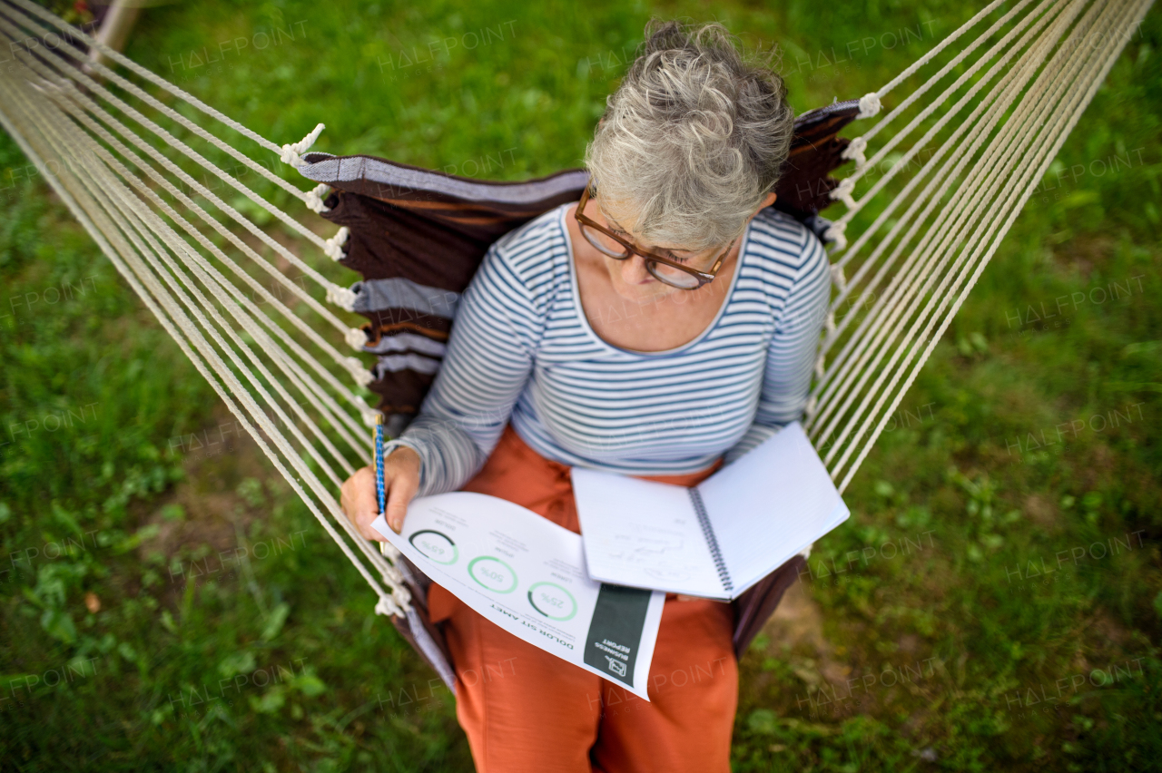 Top view of active senior woman working outdoors in garden, green home office concept.