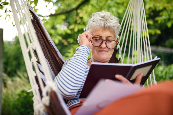 Front view portrait of active senior woman working outdoors in garden, home office concept.