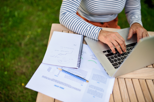 Top view of active senior woman working outdoors in garden, green home office concept.