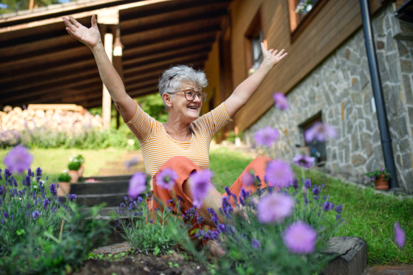 A portrait of cheerful senior woman sitting outdoors in garden, relaxing.