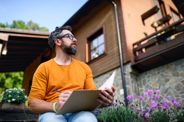 Portrait of mature man working outdoors in garden, green home office concept.