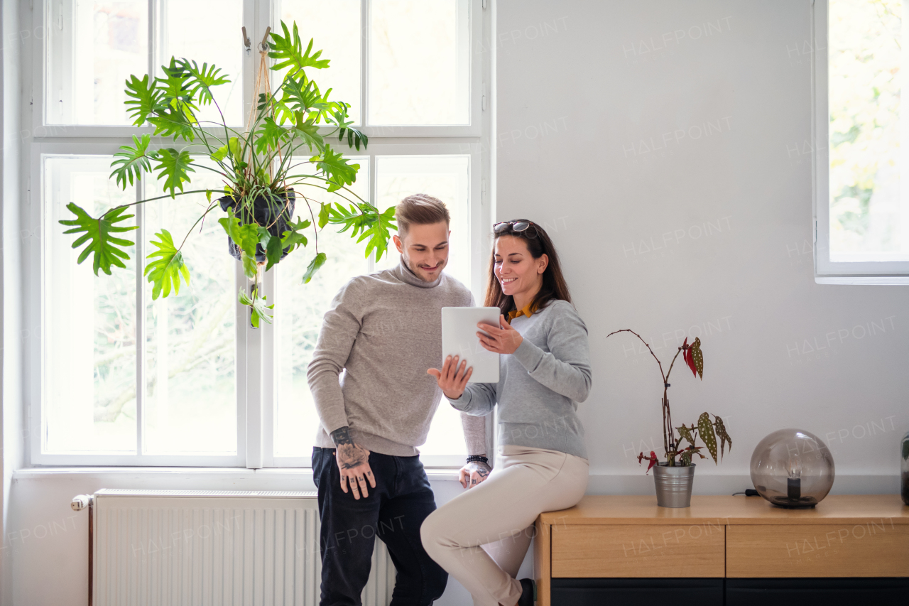 Two businesspeople with tablet standing indoors in office, working.