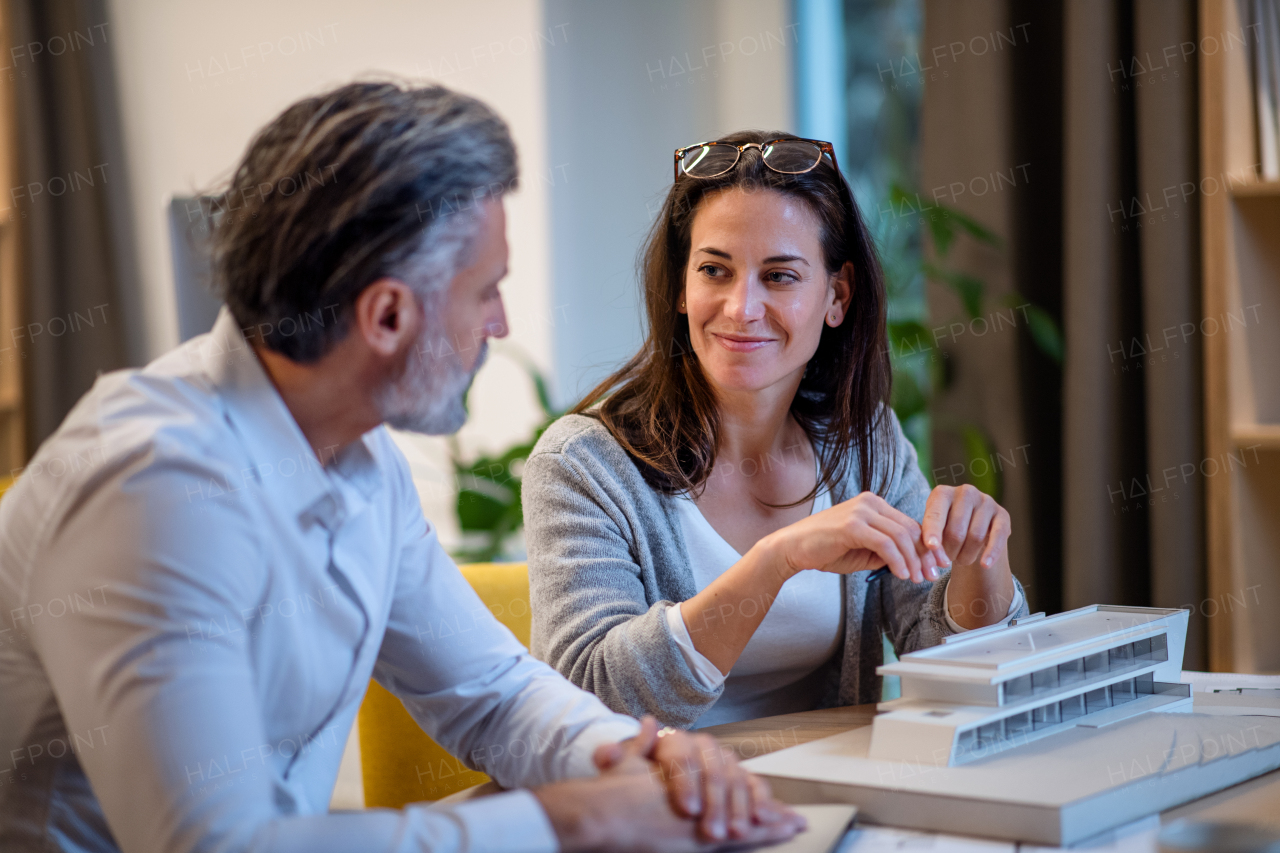 Mature architects sitting at the desk indoors in office, working.