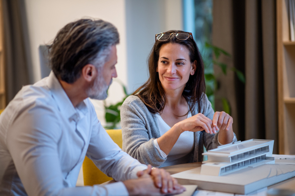 Mature architects sitting at the desk indoors in office, working.