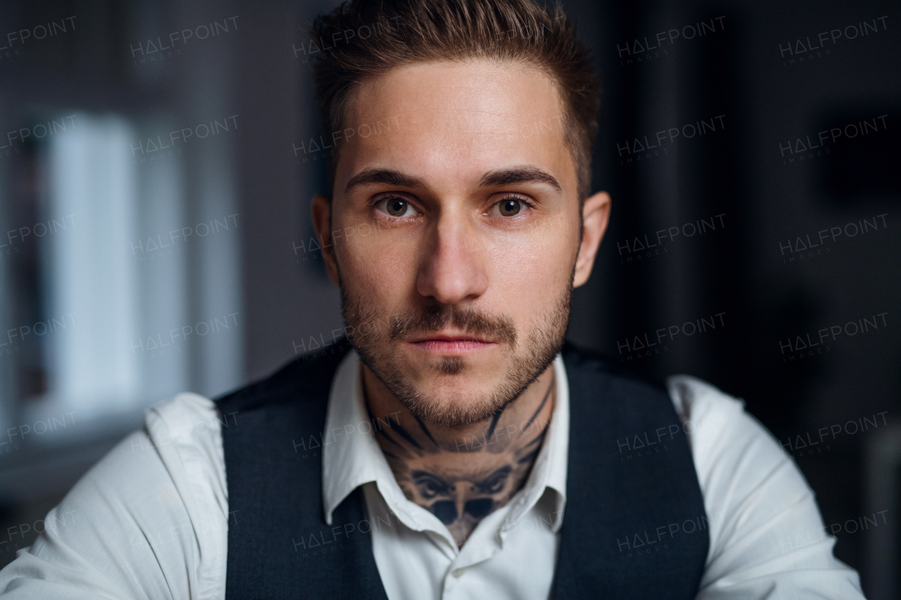 A front view of young businessman indoors in office, looking at camera.