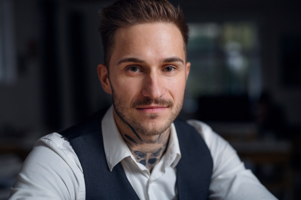 A front view of young businessman indoors in office, looking at camera.