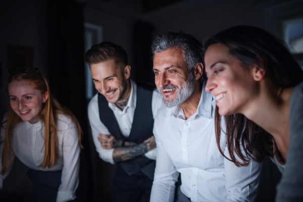 A group of businesspeople with computer indoors in office, working late.