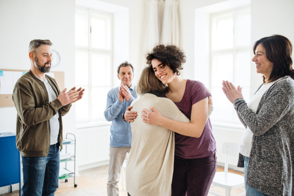 Group of men and women during group therapy, showing signs of relief.