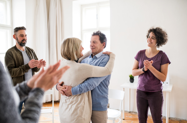 Group of men and women during group therapy, showing signs of relief.