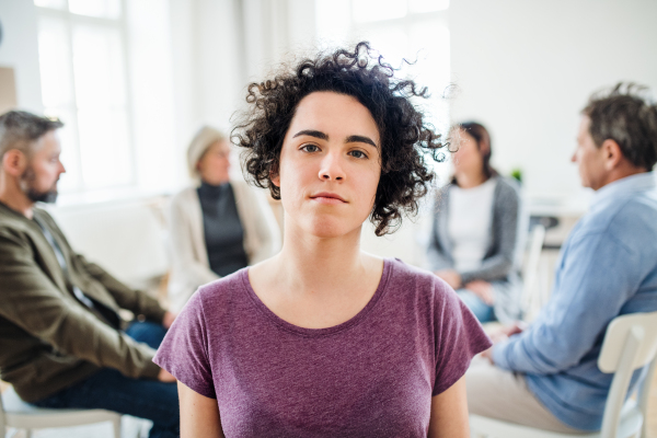 A portrait of young attractive depressed woman during group therapy.