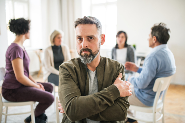 A waist-up portrait of mature angry man during group therapy.