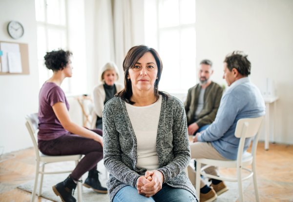 A portrait of senior depressed woman during group therapy.