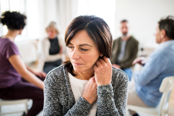 A portrait of senior depressed woman during group therapy.