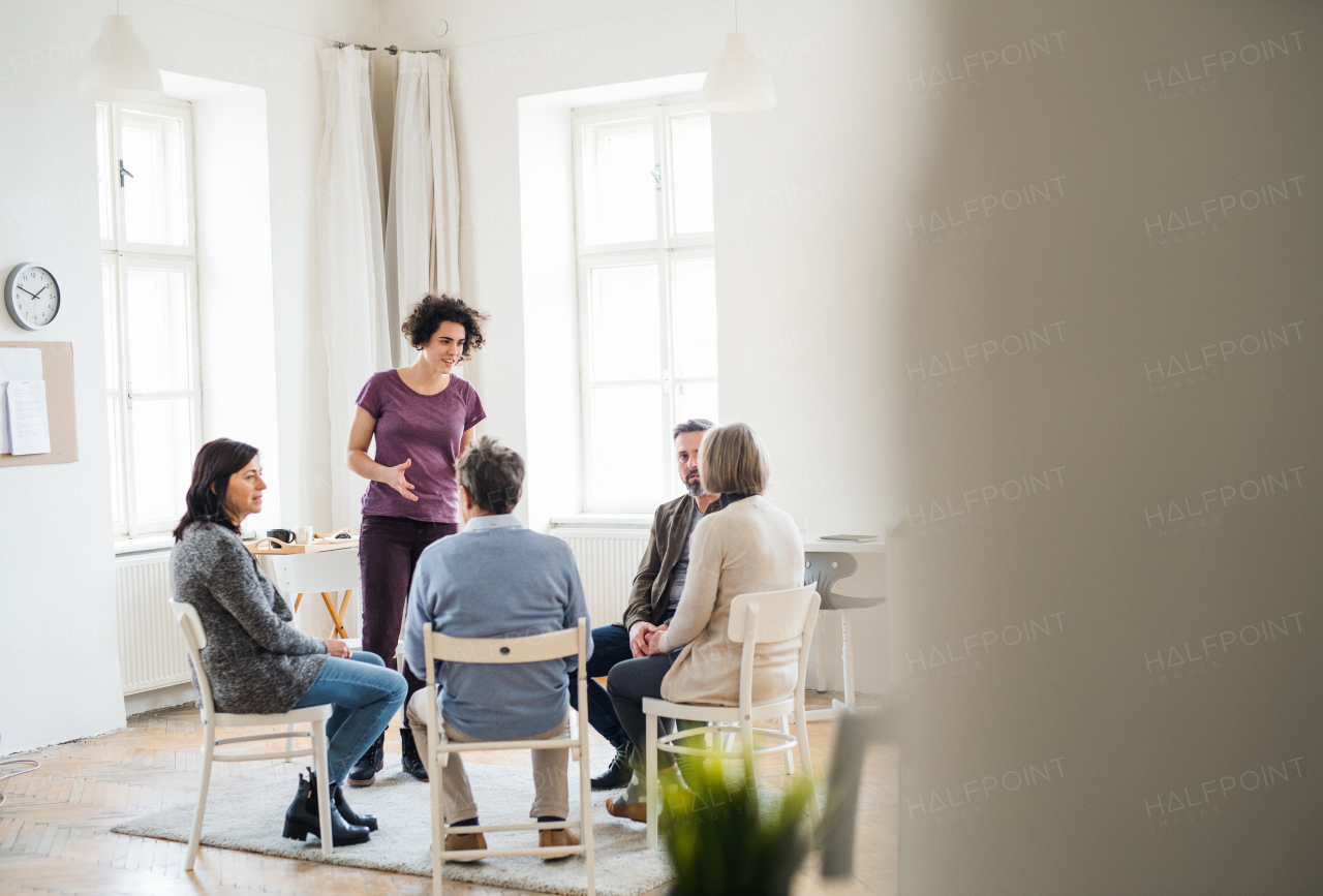 A young woman standing and talking to other people during group therapy.