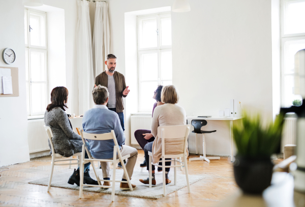 A mature man standing and talking to other people during group therapy.