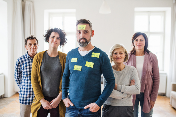 A portrait of young and old people standing with negative emotions adhesive notes during group therapy.