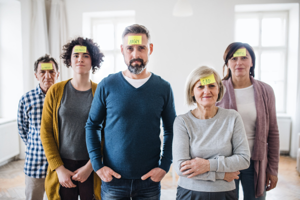 A portrait of young and old people standing with negative emotions adhesive notes during group therapy.