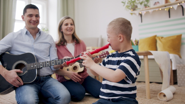 A cheerful down syndrome boy with parents playing musical instruments, laughing.