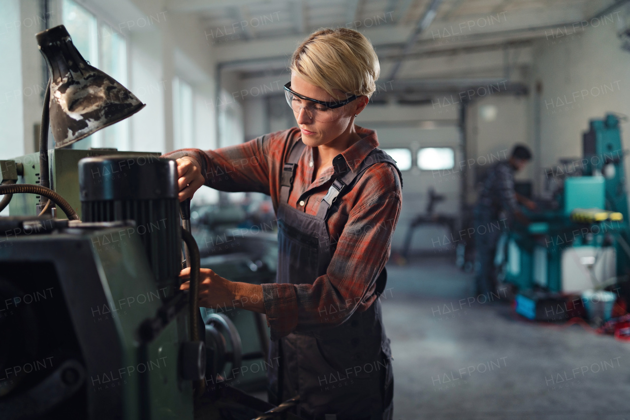 A portrait of mid adult industrial woman working indoors in metal workshop.