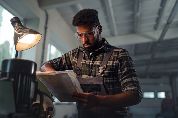 A portrait of young industrial man working indoors in metal workshop.