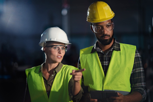 A portrait of industrial inspectors doing a general check up indoors at metal workshop.