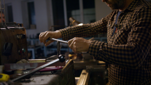 A concentrated mature industrial man working indoors in metal workshop.