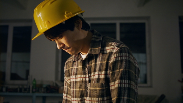 A concentrated Japanese industrial man working indoors in metal workshop.