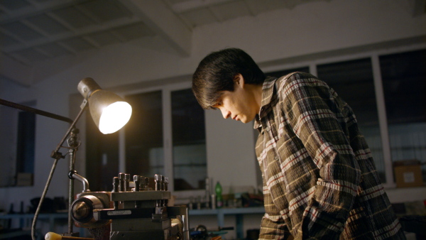 A concentrated Japanese industrial man working indoors in metal workshop