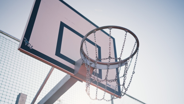 Male basketball player dunks the ball with two hands. Close up on the rim, net and ball.