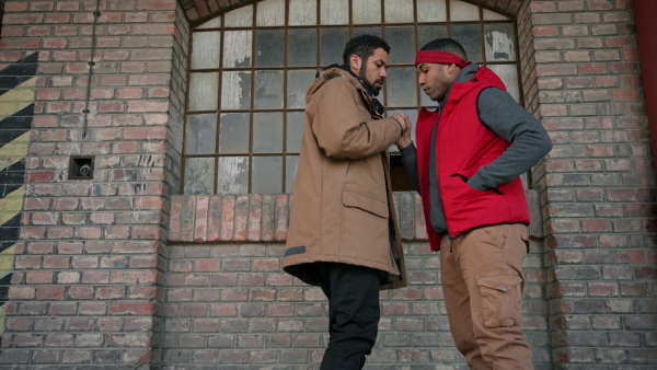 Two young men dealing drugs in the street, low angle view.