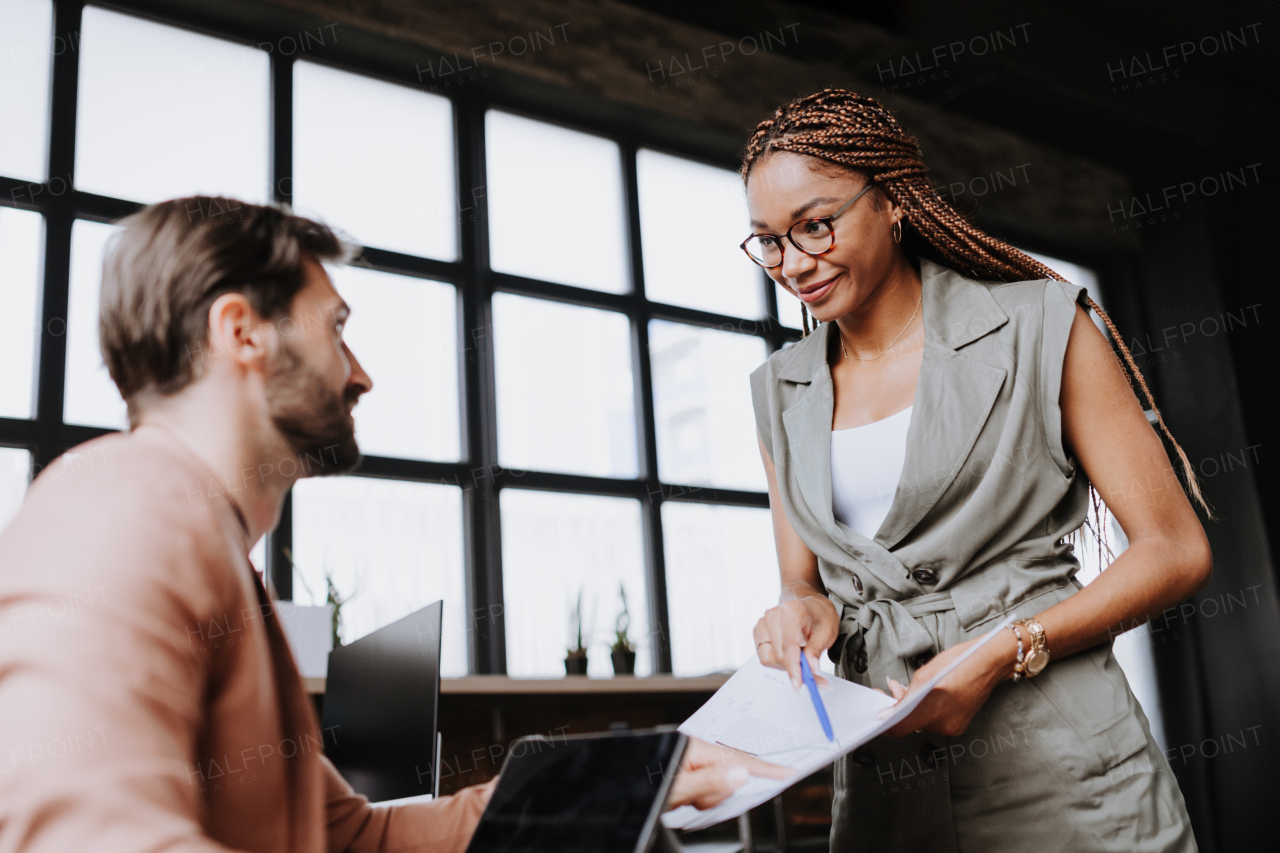 People in coworking space sharing ideas, collaboring, talking about project. Group of freelancers and remote businesspeople working in shared work area. Concept of coworking as modern working arragement. Working remotely from coffee shop.