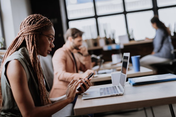 Beautiful businesswoman working on laptop in modern office. Group of freelancers working in shared work area. Concept of coworking, common workspaces for business, startups. Working remotely from coffee shop.