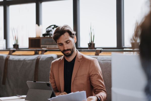 Businessman reading documents in modern office or coworking area. Working remotely from the coffee shop. Concept of coworking, common workspaces for business, startups.