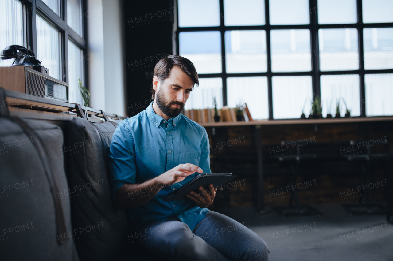 Handsome businessman preparing for meeting, working on presentation on tablet, sitting in modern office. Working remotely from coffee shop.