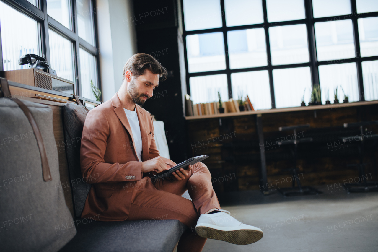 Handsome businessman preparing for meeting, working on presentation on tablet, sitting in modern office. Working remotely from coffee shop.