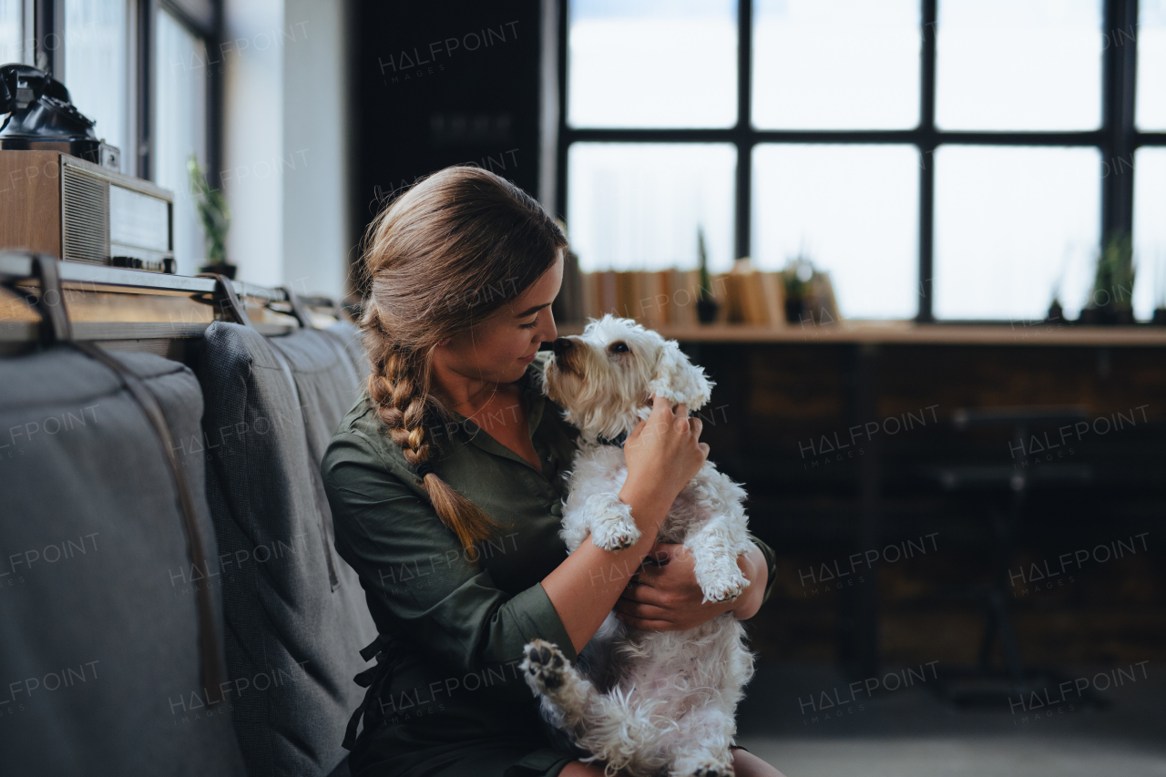 Portrait of beautiful young woman holding her dog and smiling. Cute white dog in arms of loving owner. With dog in coffe shop.