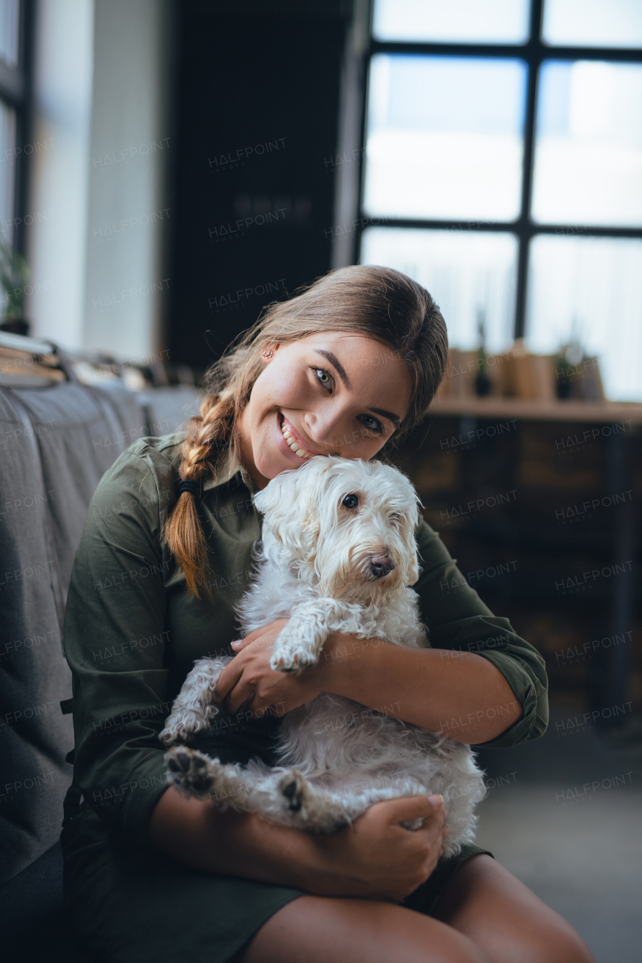 Portrait of beautiful young woman holding her dog and smiling. Cute white dog in arms of loving owner. With dog in coffe shop.