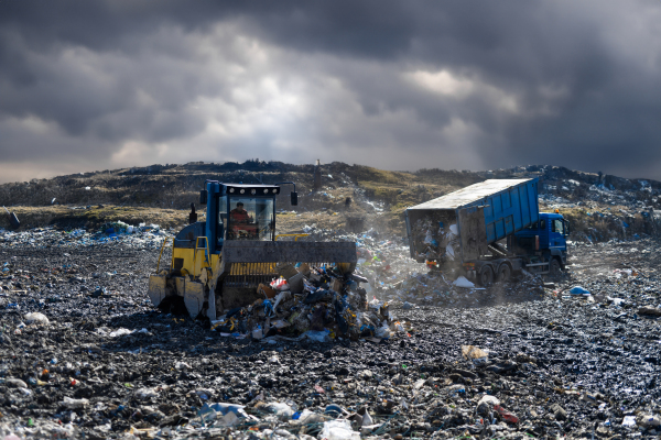 Garbage truck unloading waste on landfill, environmental concept. Copy space.