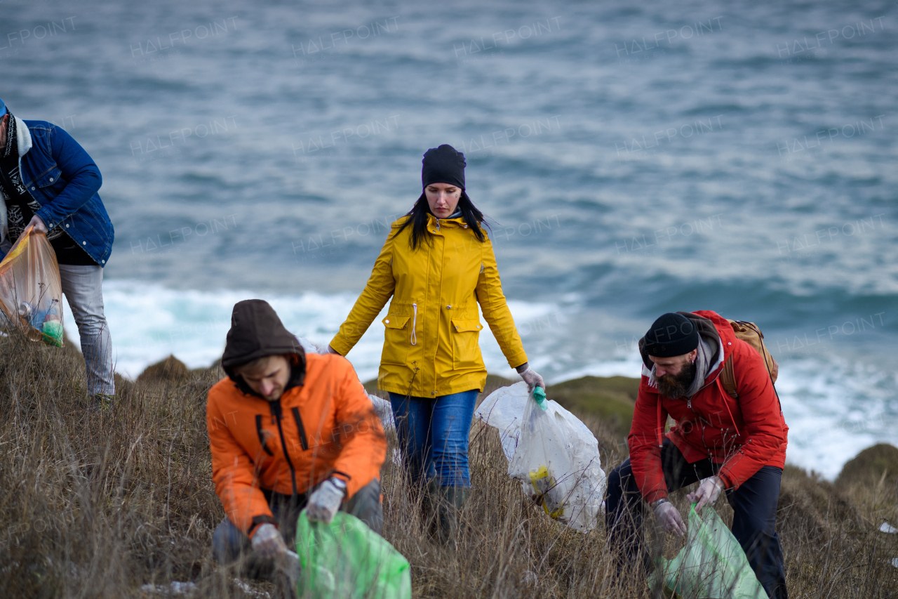 Group of activists picking up litter along riverbank. River clean-up. Environmental pollution, eco activism. and plogging concept.