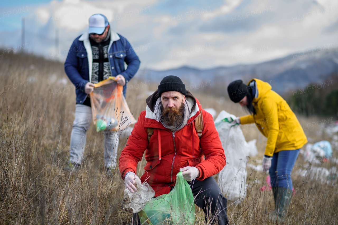 Group of activists picking up litter in the nature, environmental pollution, eco activism. and plogging concept.