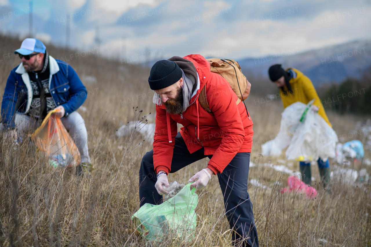 Group of activists picking up litter in the nature, environmental pollution, eco activism. and plogging concept.